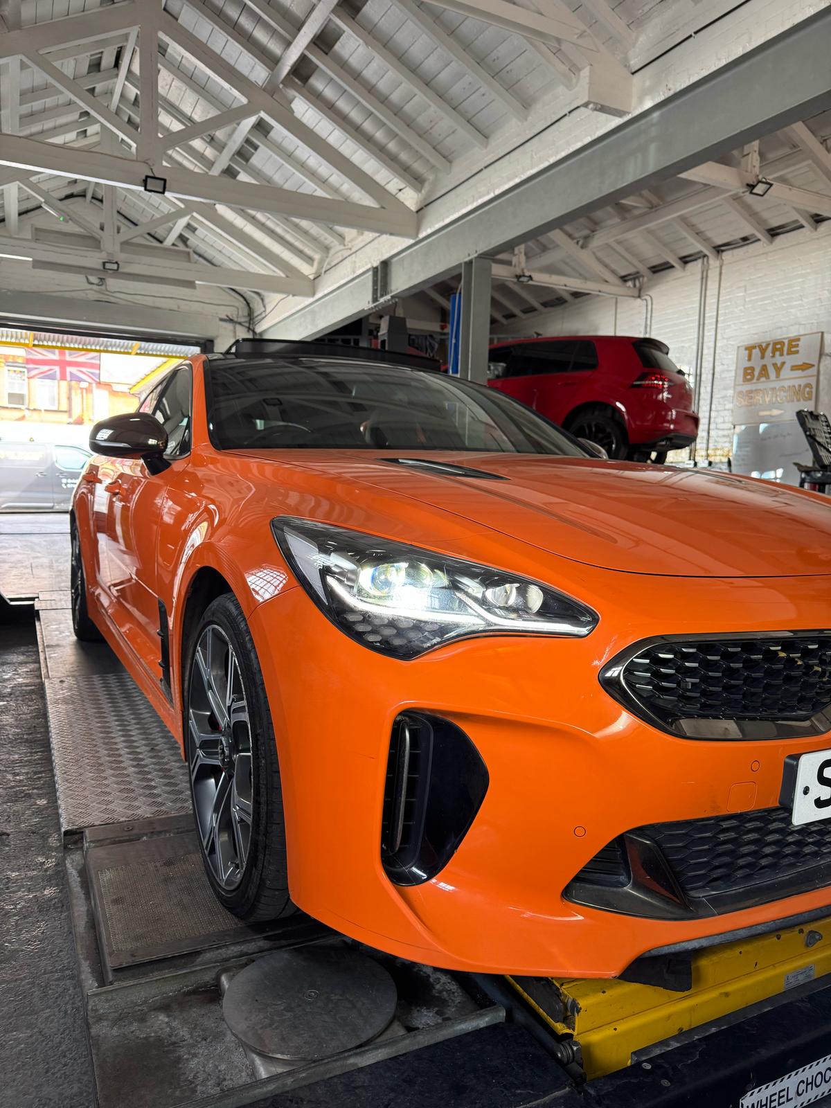 An orange car on the workshop ramp being inspected